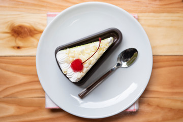 Cake slice top view with cherry fruit and cream on white palte on the table - Delicious green tea cheese cake