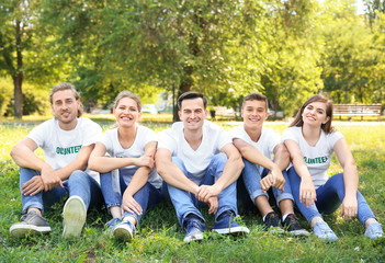 Group of volunteers sitting on green grass outdoors