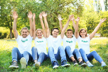 Group of volunteers sitting on green grass outdoors