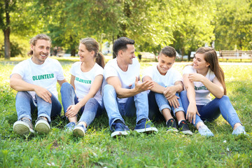 Group of volunteers sitting on green grass outdoors