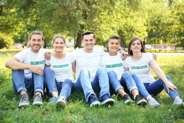 Group of volunteers sitting on green grass outdoors
