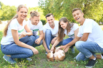 Group of volunteers with cute dog outdoors