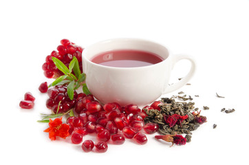 Parts of a pomegranate with pomegranate seeds and leaves, flowers, dry tea of carcade and full cup of tea isolated on white background