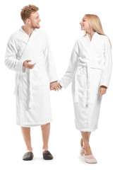 Fototapeta premium Happy young couple in bathrobes on white background