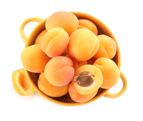 Pot with tasty ripe apricots on white background