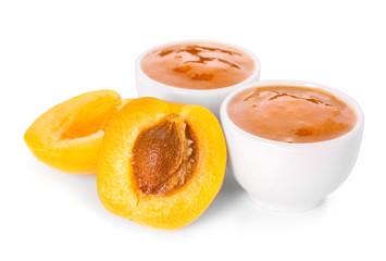 Fototapeta na wymiar Bowls with tasty apricot jam on white background