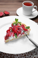 Plate with piece of tasty strawberry cake on table