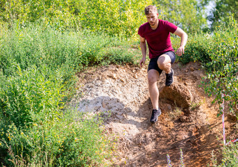 Tired runner running in the cross-country race at sunny day
