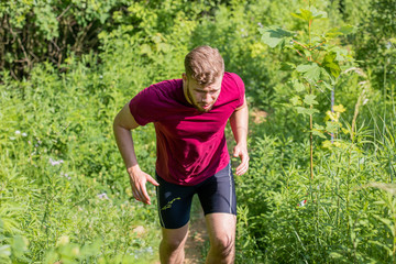 Tired runner running in the cross-country race at sunny day