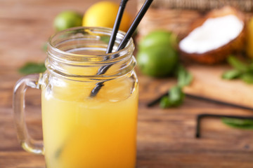 Mason jar of fresh pineapple juice on wooden table, closeup