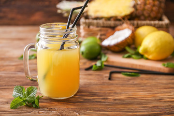 Mason jar of fresh pineapple juice on wooden table
