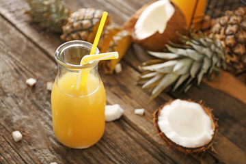 Bottle of fresh pineapple juice and coconut on wooden table