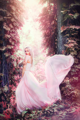Beauty romantic young woman in long chiffon dress with gown posing in fantasy misty forest....