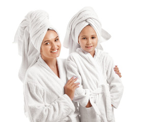 Mother and her little daughter in bathrobes on white background