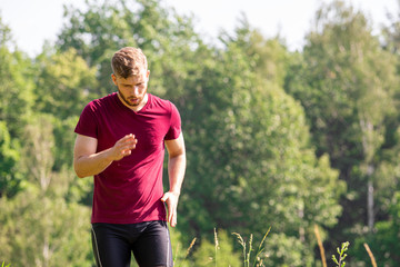 Tired runner running in the cross-country race at sunny day