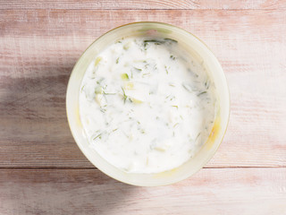 Sauce made from yogurt and vegetables in a cup on a brown wooden background
