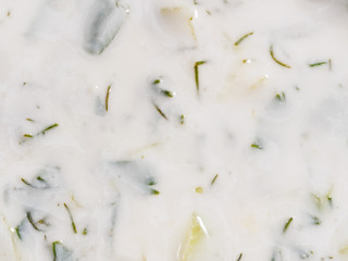 Sauce made from yogurt and vegetables in a cup on a brown wooden background. Close up