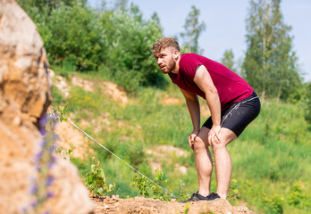 Tired runner preparing before overcoming rocks obstacles in the cross-country race
