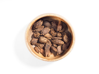 Black cardamom (Amomum subulatum) on a brown wooden cup on a white background