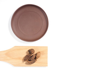 Black cardamom (Amomum subulatum) on spoon on a white background with clay plate