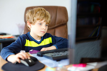 Little kid boy making school homework on computer notebook. Happy healthy child searching...