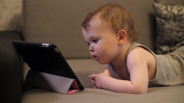 Little serious and lonely child Girl sitting and looking on tablet laptop
