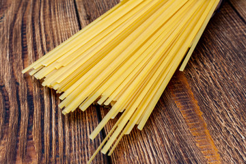spaghetti, macaroni, pasta, linguine durum wheat Italian thin long on wooden background close up...