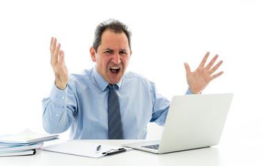 Overwhelmed and desperate mature businessman working with laptop feeling angry and furious at office