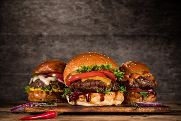 Close-up of home made tasty burgers on wooden table. - obrazy, fototapety, plakaty