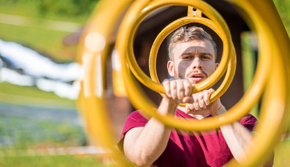 Portrait of fit man overcomes hanging rings obstacles at the extreme race