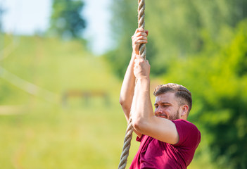 Overcome obstacle using rope during extreme race in the boot camp