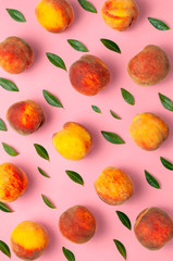 Flat lay composition with peaches. Ripe juicy peaches with green leaves on pink background. Flat...