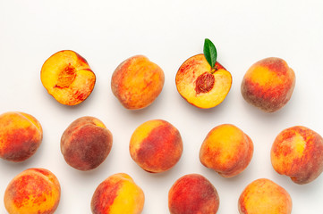 Flat lay composition with peaches. Ripe juicy peaches with green leaves on white background. Flat lay, top view, copy space. Creative peaches pattern. Fresh organic food. Harvest concept