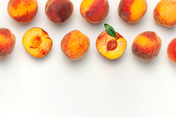 Flat lay composition with peaches. Ripe juicy peaches with green leaves on white background. Flat lay, top view, copy space. Creative peaches pattern. Fresh organic food. Harvest concept