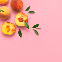 Flat lay composition with peaches. Ripe juicy peaches with green leaves on pink background. Flat lay, top view, copy space. Fresh organic fruit, vegan food. Harvest concept.