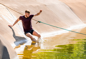Fit man jumping to the water during obstacle race training in boot camp