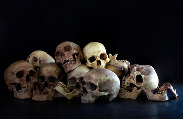 Pile of skulls put on dark floor and black background dim light