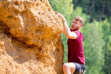 Fit man climbing on rocks obstacles in the boot camp