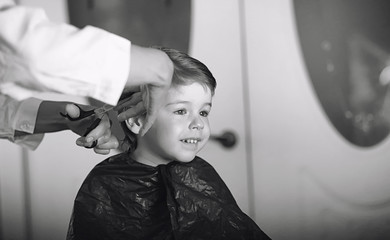 Hairdresser and boy. The boy is doing his hair. Cut hair child in the hairdresser.