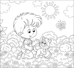Smiling little boy playing with a small cheerful kitten among flowers on grass of a lawn on a sunny summer day, black and white vector illustration in a cartoon style for a coloring book