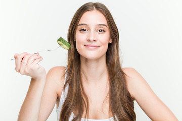 Young caucasian woman eating cucumber happy, smiling and cheerful.