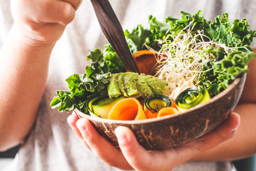 Healthy vegan lunch in a coconut bowl. A child eating Buddha bowl.