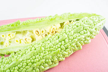 Fresh green vegetable bitter gourd on red cutting board