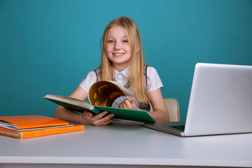 Little girl sitting in the classroom with book infront of computer