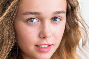 portrait of a beautiful young blonde smiling girl with long hair on a white background