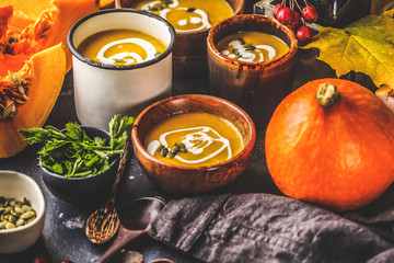 Autumn pumpkin soup puree with cream in cups, the autumn scenery. Healthy vegan food concept.