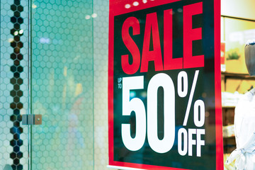 Sale sign 50 percent in a fashion clothes shop display window