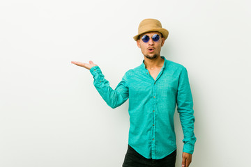 Young hispanic man wearing a summer clothes impressed holding copy space on palm.