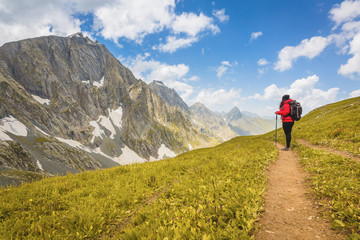 Fototapeta na wymiar Solo Woman trekking/hiking at Great lakes of Kashmir, India. Red,green and blue colors of Himalayas. Wanderlust Nature image. Landscape, Blue skies and Turquoise lake. Valleys and meadows . Wallpaper