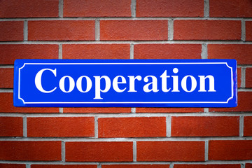 Cooperation street sign on brick wall